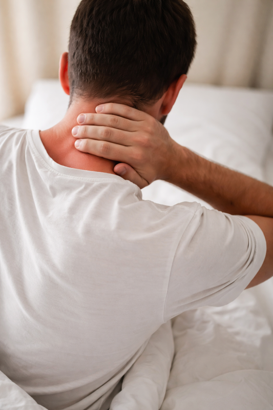 Douleur cervicale au réveil, personne tenant sa nuque avec la main, posture du matin sans visage visible.
