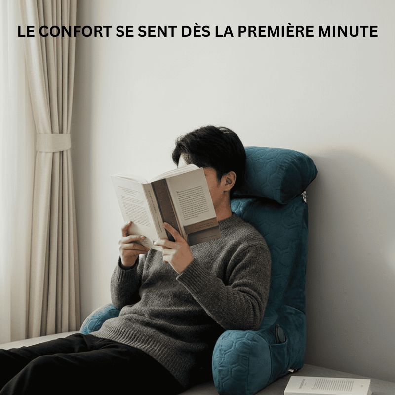 Personne semi-allongée sur un lit, adossée à un coussin de lecture, en train de lire un livre dans une chambre épurée à la lumière naturelle.