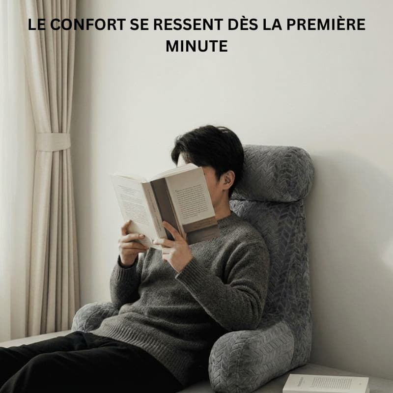 Personne semi-allongée sur un lit, adossée à un coussin de lecture, en train de lire un livre dans une chambre épurée à la lumière naturelle.