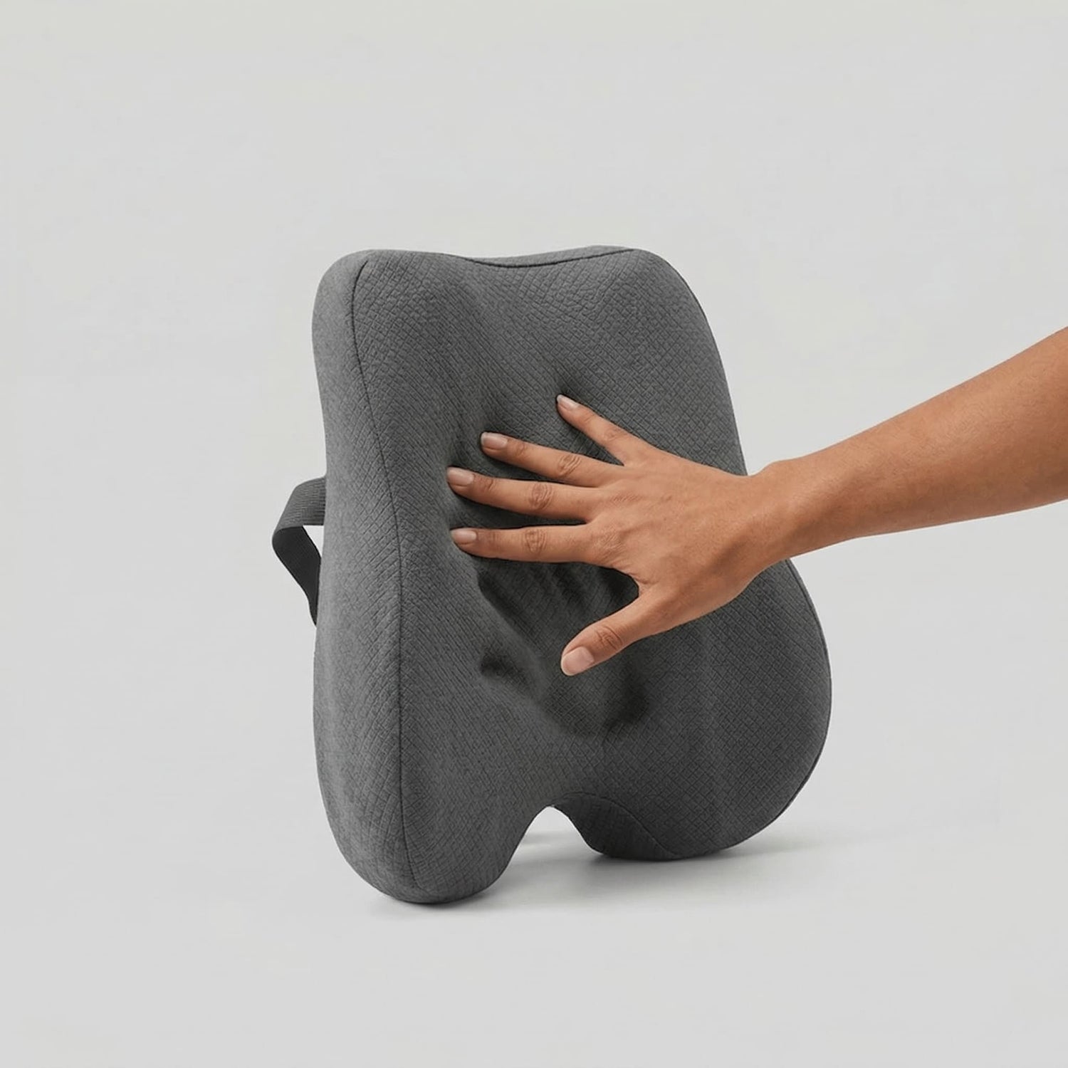 Main appuyant sur le coussin lombaire Nerua montrant la mousse à mémoire de forme qui épouse la courbure du dos
