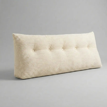 Coussin tête de lit triangulaire en velours côtelé beige posé sur un lit