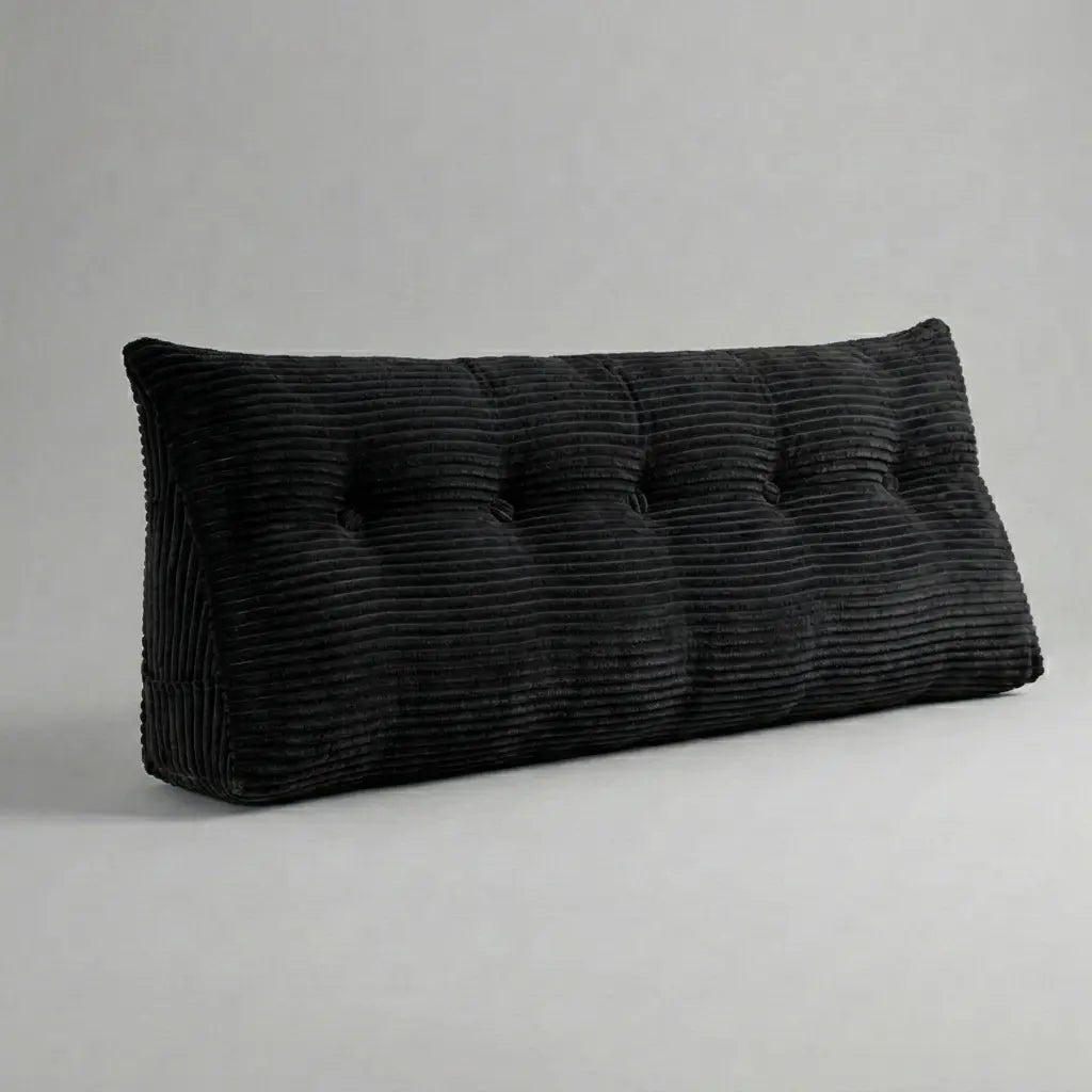 Coussin tête de lit triangulaire en velours côtelé noir posé sur un lit