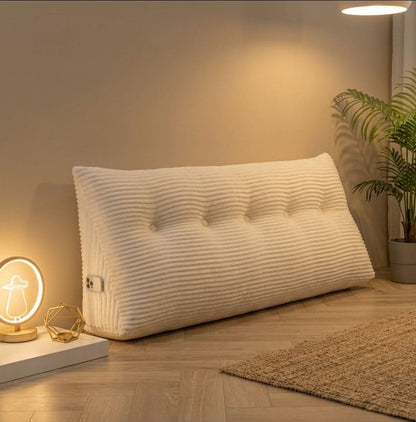 Coussin tête de lit triangulaire posé au sol contre un mur